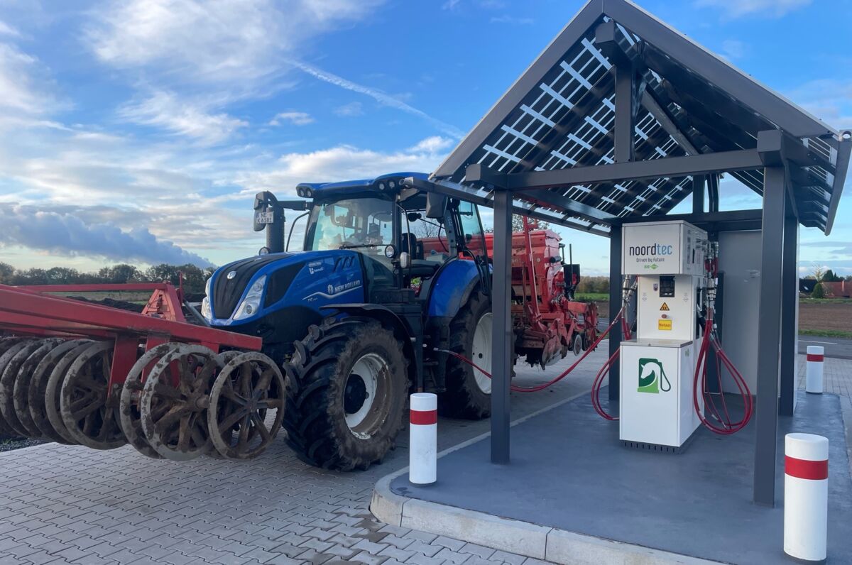 Traktor mit Landmaschinen vorne und hinter der betankt wird, Biokraftstofftankstelle